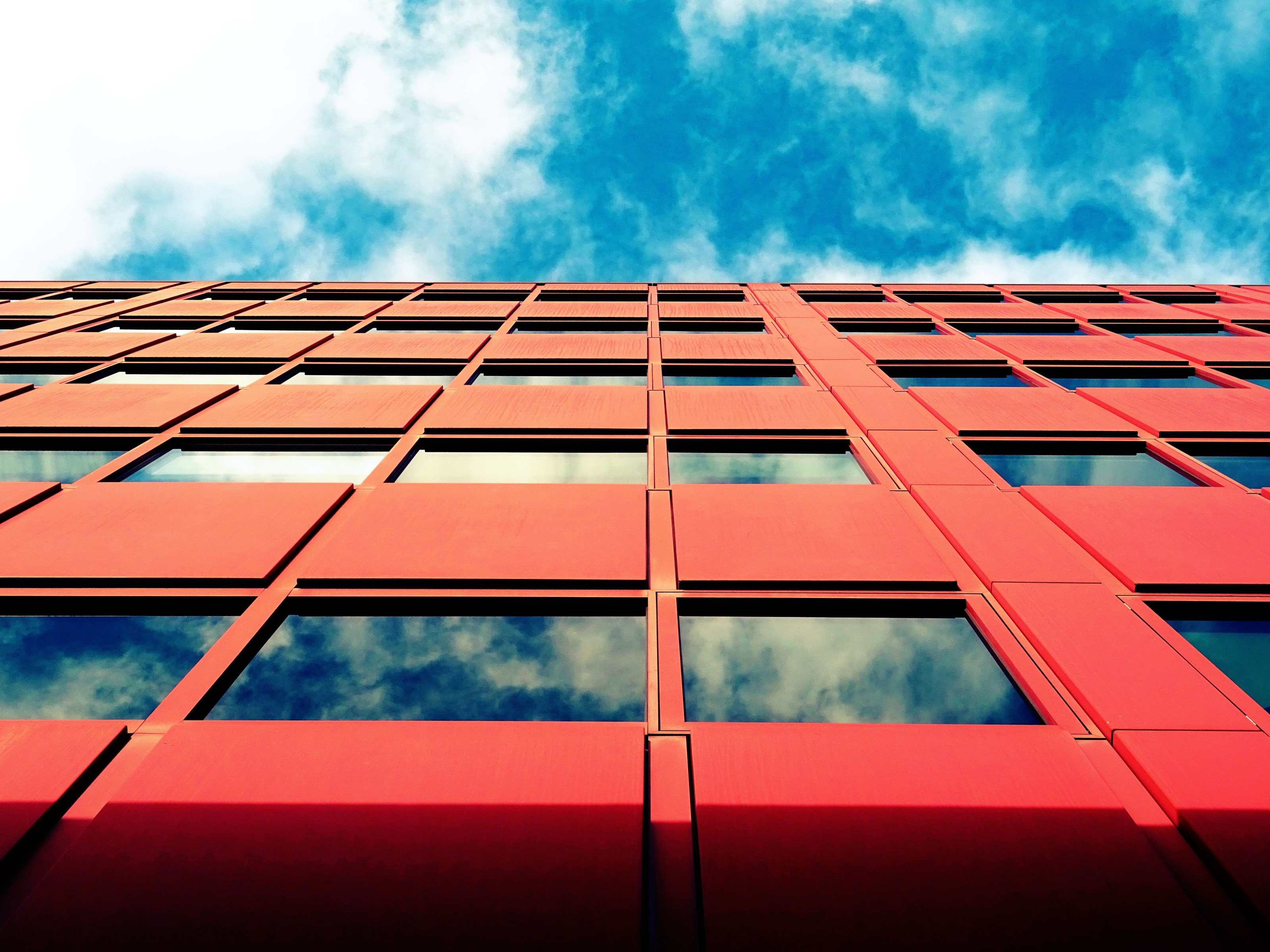 A red facade grid seen from below against a blue sky