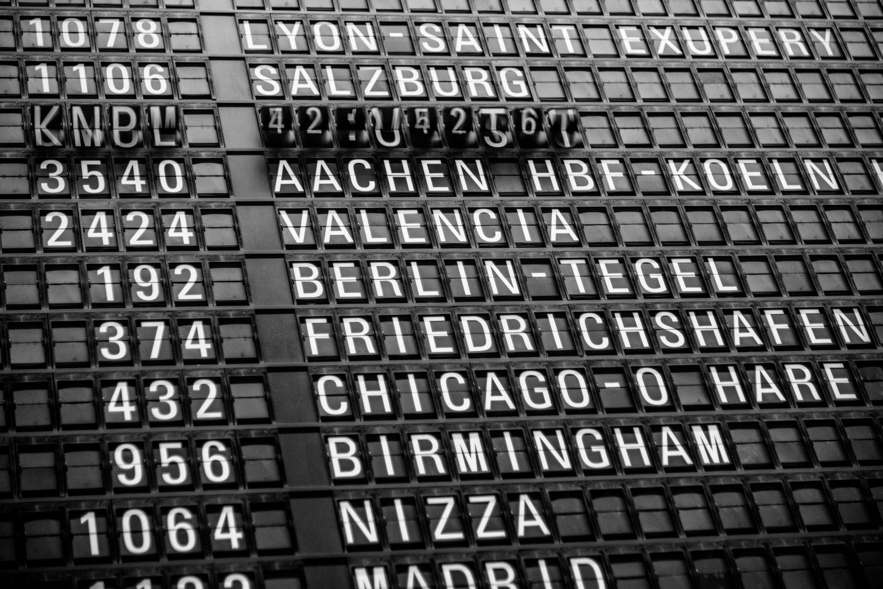 A split-flap departures board listing destinations and flight numbers