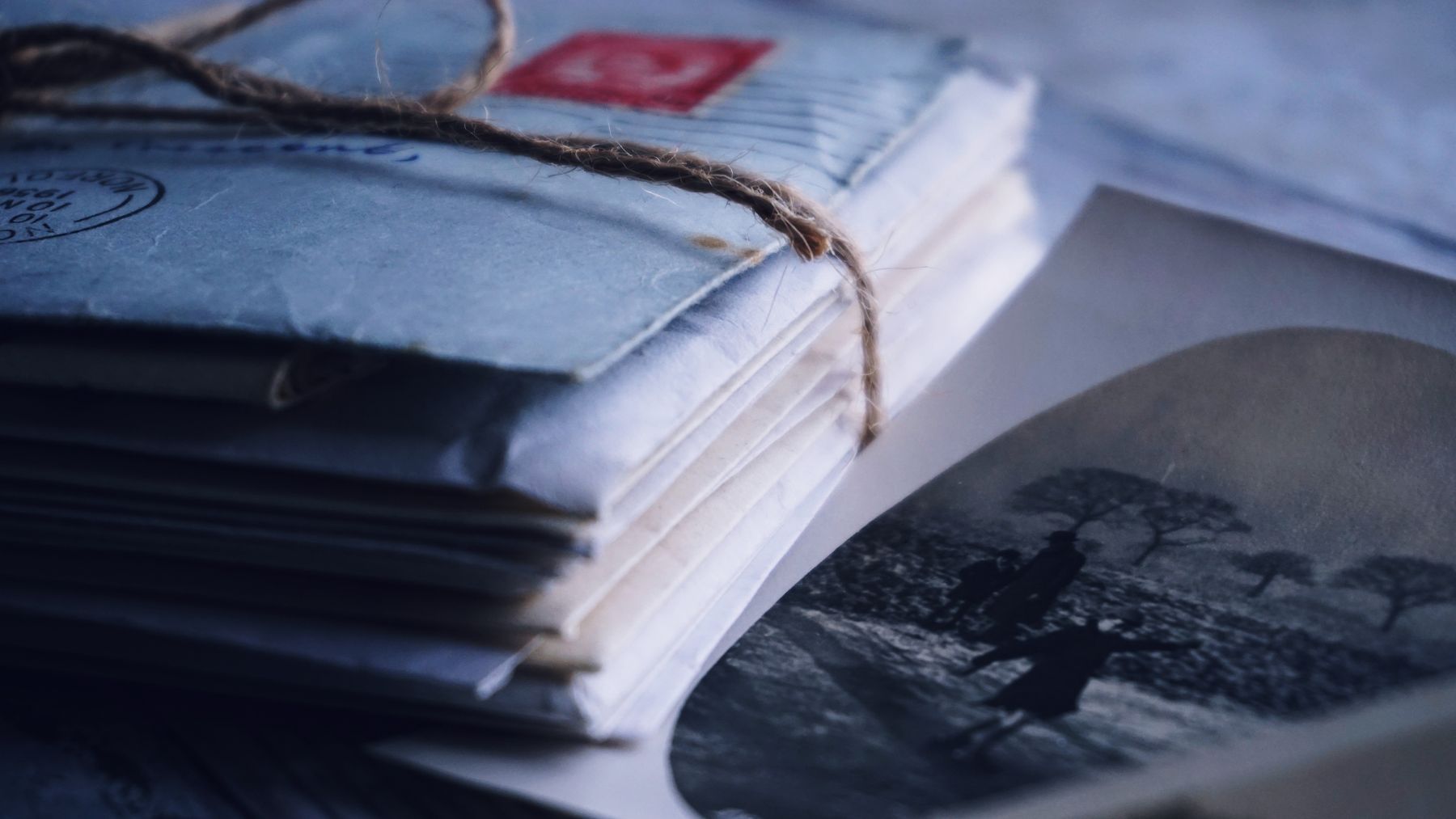 A bundle of old letters tied with twine, resting on a photograph