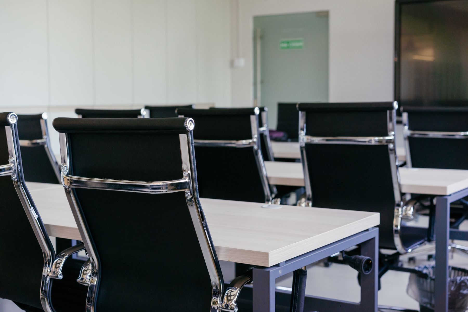 An empty meeting room with black chairs lined along a table