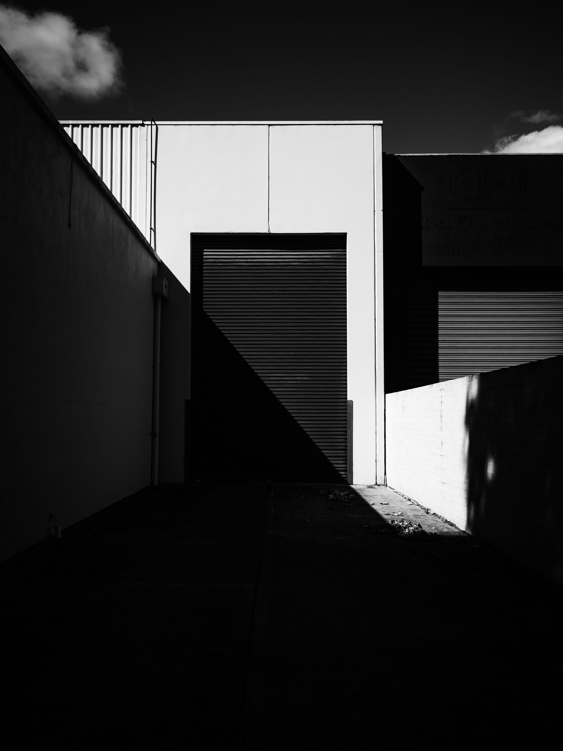 A warehouse loading dock with a roller shutter in stark light and shadow